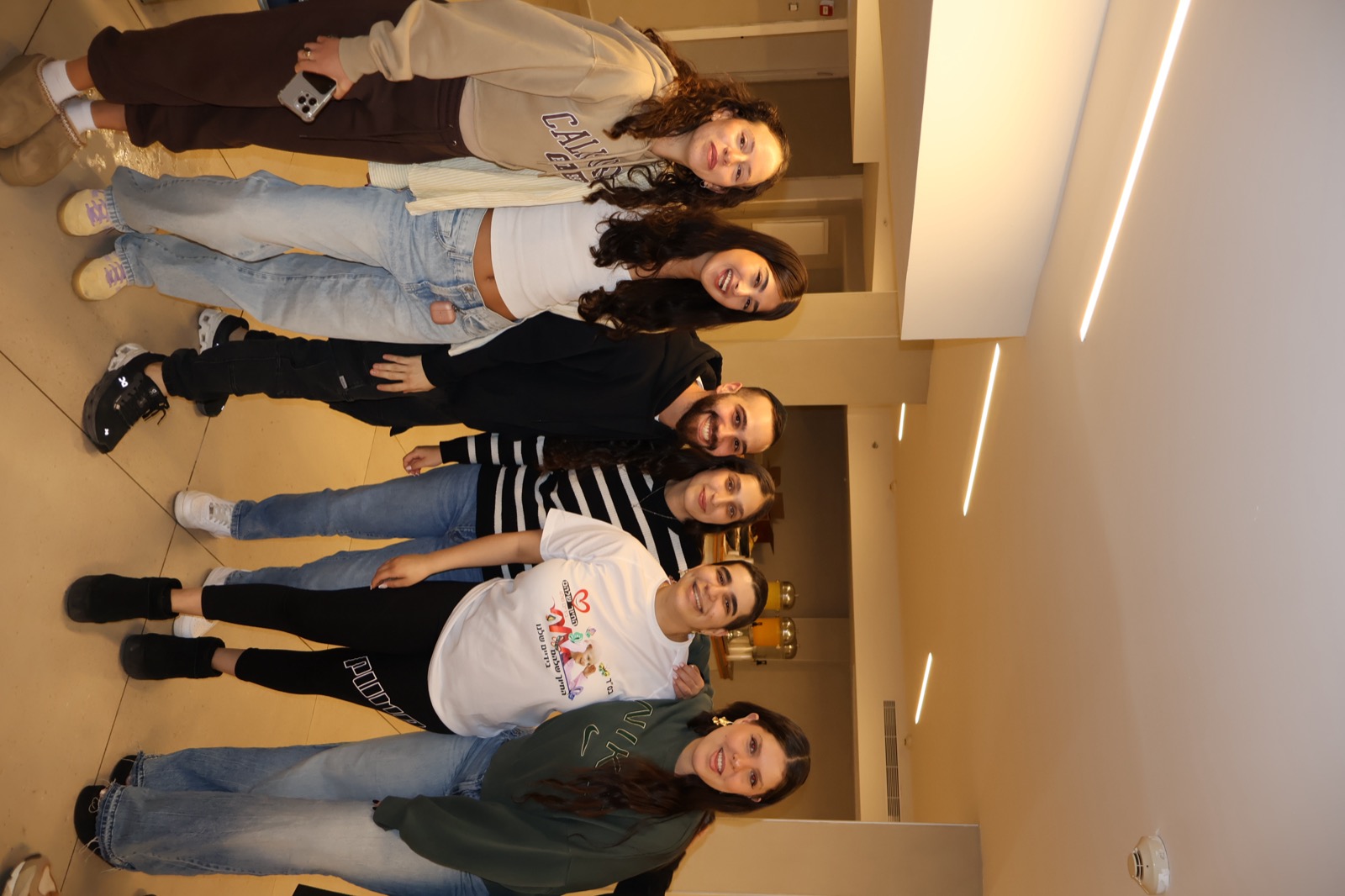 חמישה מתנדבים ונתמכים מחויכים בחולצות ארגון